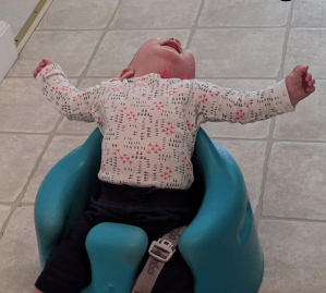 a seated baby with head thrown back and arms up having a bad day